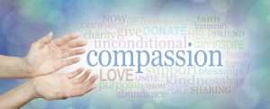 Compassion banner -  wide banner with a woman's hands in an open needy position with the word COMPASSION to the right surrounded by a relevant word cloud on a soft blue and white bokeh background