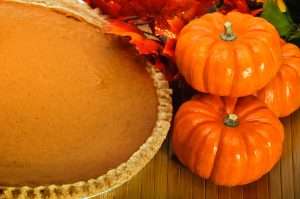 Pumpkin pie with autumn leaves and pumpkins.